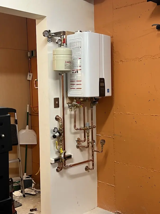 Plumbing technician inspecting water heater connections in Raymond